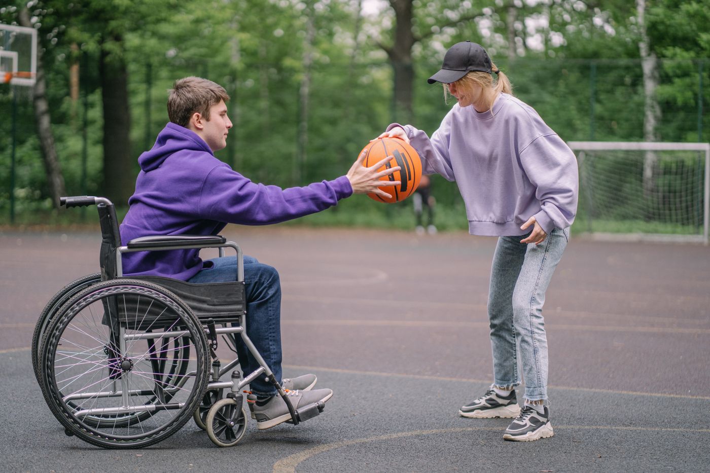 A young man in a wheelchair playing basketball with a friend