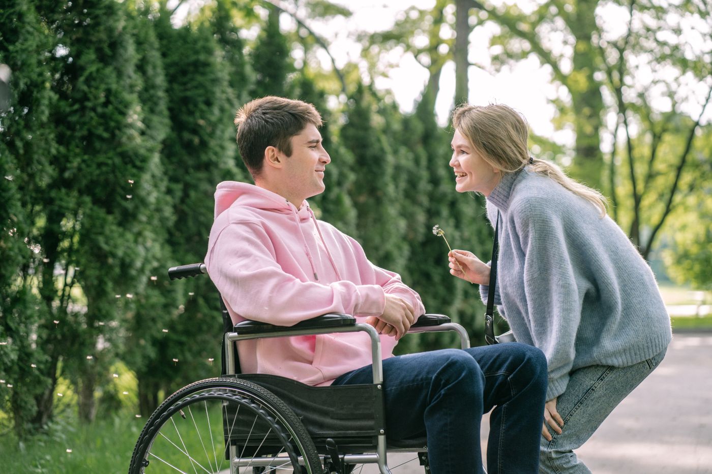 A support worker chatting with a young man in a wheelchair in a park